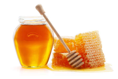 Honey in glass jar with wooden dipper and honeycombs, isolated on the white background, clipping path included.の写真素材