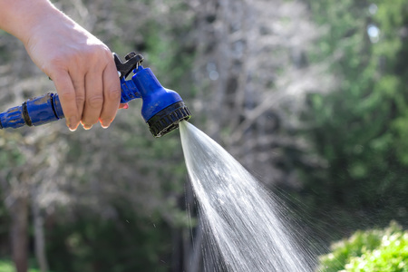 Watering garden equipment - hand holds the sprinkler hoseの写真素材
