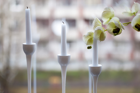 Three white candles in the elegant candle holder with an orchid blossomの写真素材