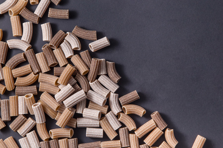 Italian raw colored whole wheat pasta on black backgroundの写真素材