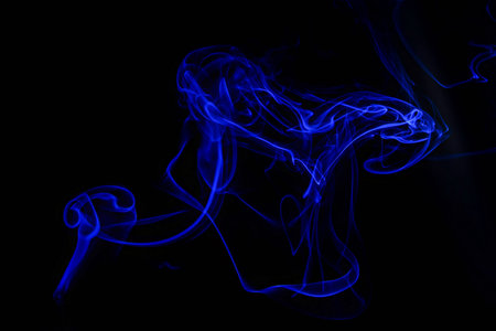 Abstract blue smoke swirls over black background