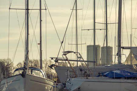 Yacht masts and various yachts on city center on the background