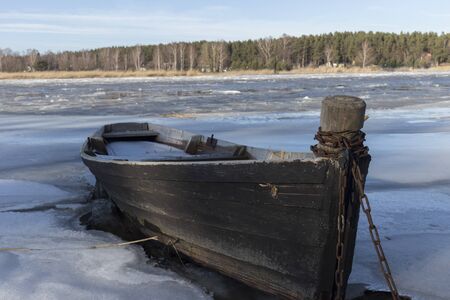Winter scene of old wooden boat on ice of frozen lake.の写真素材