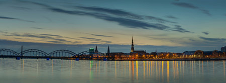 Night view on the illuminated riverside with reflection on the river in Riga, Latvia