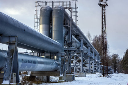 Large industrial pipes on an elevated metal structure in a snowy, industrial setting. Pipeline or processing plant. Perfect for industrial, engineering, or infrastructure projects.の写真素材