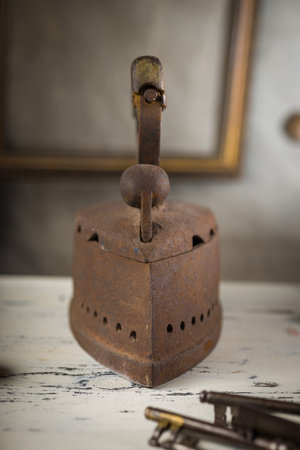 Rusty Vintage Iron with Wooden Handle Sitting on old Tableの写真素材