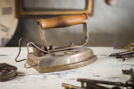 A vintage electric iron with a rustic patina, placed on a workbench. The antique appliance exudes a sense of nostalgia and craftsmanship.の写真素材
