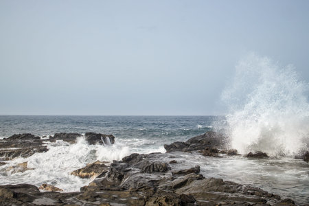 Waves crashing against a rocky shoreline in Gran Canaria. Dramatic coastal scene with powerful waves...