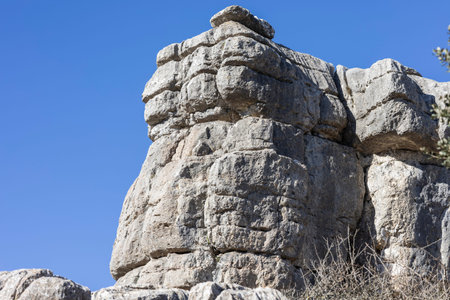 A natural rock formation stands tall in El Torcal, Spain. Visitors explore the area while enjoying...