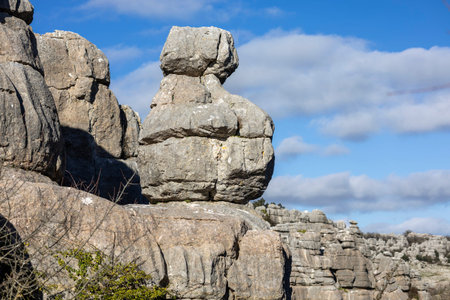 Visitors walk among giant stone formations at El Torcal in Spain. The rocks stand tall against a...