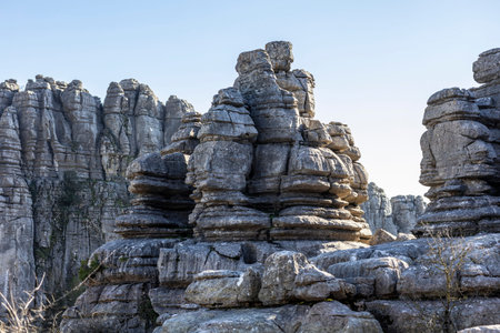 A group walks among large stone structures in El Torcal, Spain. The sun shines on the rocks,...