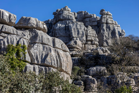 Visitors explore the rock formations of El Torcal in Spain. The sun shines brightly, illuminating...