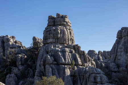 Visitors look up at the tall rock formations in El Torcal, Spain, during daytime. The sun shines...