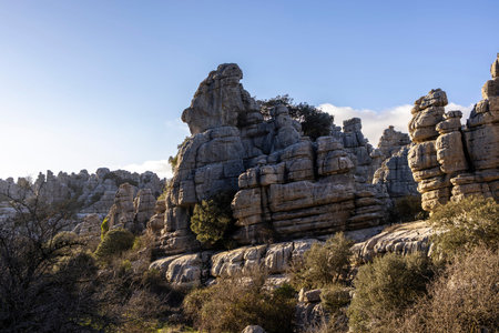 Visitors walk among the unique rock formations of El Torcal in Spain. They admire the natural shapes...