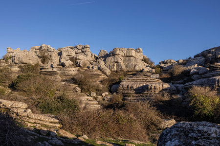 Visitors explore the unique rock formations of El Torcal in Spain. The scene shows large stones and...
