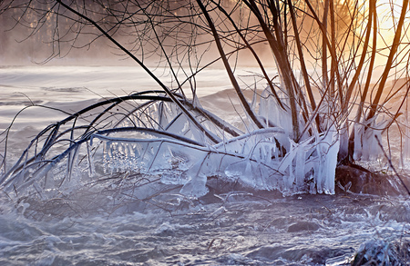 landscape shot of the Roer River in winter with snow, ice and icicles at sunrise, Dueren, Germanyの写真素材