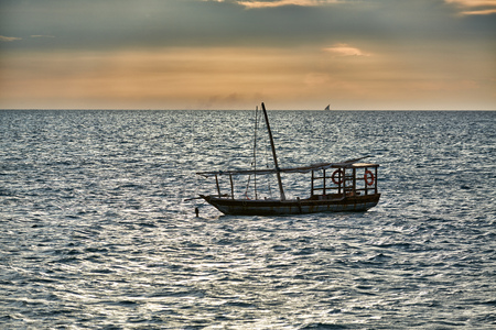 Typical dhow swings in sea at sunset, Zanzibar, Tanzania, Africaの写真素材