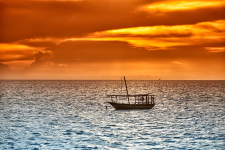 Typical dhow swings in sea at sunset, Zanzibar, Tanzania, Africaの写真素材