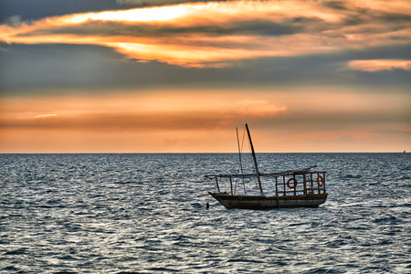 Typical dhow swings in sea at sunset, Zanzibar, Tanzania, Africaの写真素材