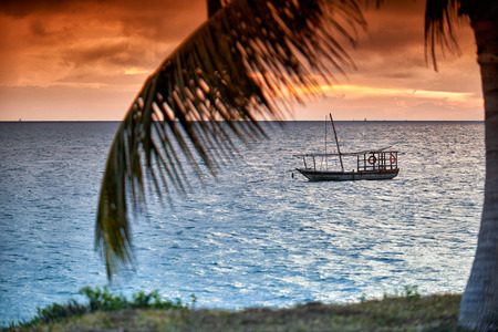 Typical dhow and palm leaf swings in sea at sunset, Zanzibar, Tanzania, Africaの写真素材