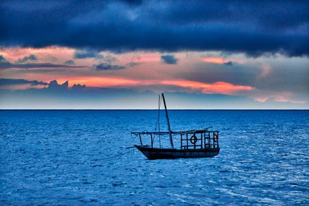 Typical dhow swings in sea at sunset, Zanzibar, Tanzania, Africaの写真素材