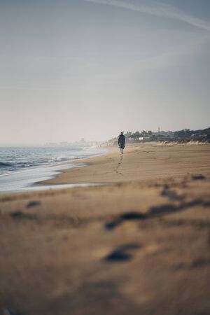 Beautiful woman walking on an empty beach in Portugal, leaving foot steps behindの写真素材