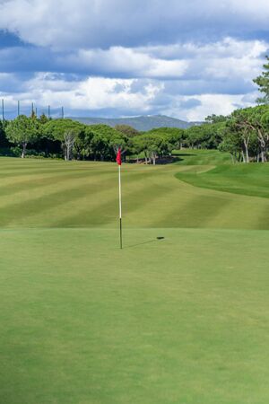 Beautiful golf course in summer with red golf flag and green grassの写真素材