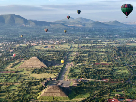 Hot air balloons flying above pyramids of Teotihuacán Mexico with a beautiful landscape and a nice...