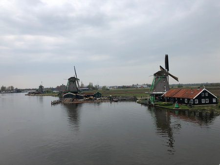 Windmills and a house by the side of the canal in Zaanse Schans, Netherlands
