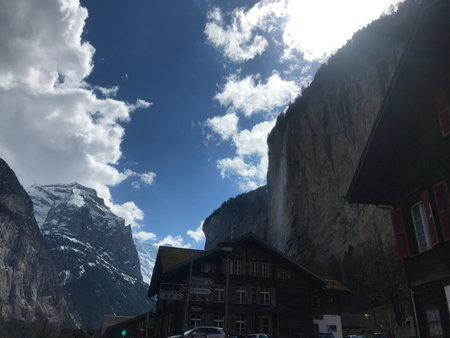 waterfall in Lauterbrunnen with some houses blue sky with clouds and mountainsの写真素材
