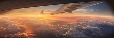Wing of airplane flying above clouds at sunset. Panoramic viewの素材