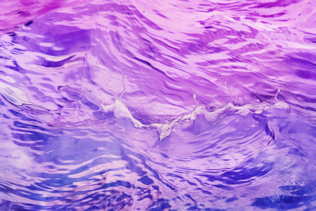 Abstract background of the water surface with ripples and waves in purple tones.の素材