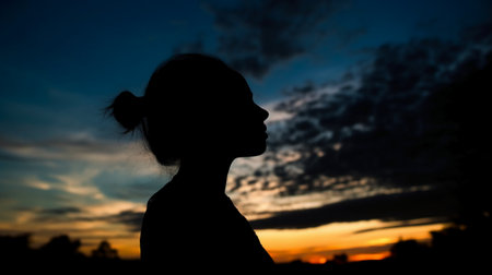 Silhouette of a young girl in the evening at sunset.の素材