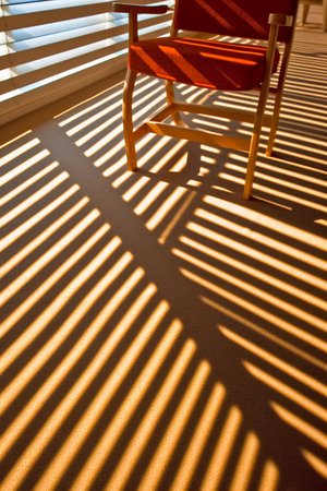 Wooden chair in sunlight with shadows from blinds on the wallの素材