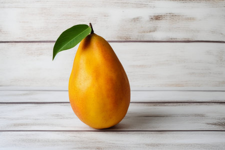 Ripe yellow pear with green leaf on a white wooden background.の素材
