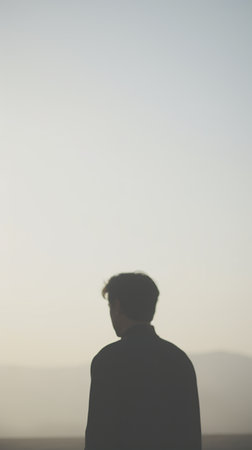 Silhouette of a young man on the top of the mountainの素材