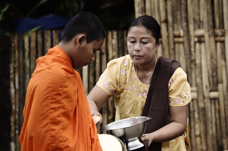 Sangklaburi, Thailand - May 11,2010 - Give food offerings to a Buddhist monkのeditorial素材