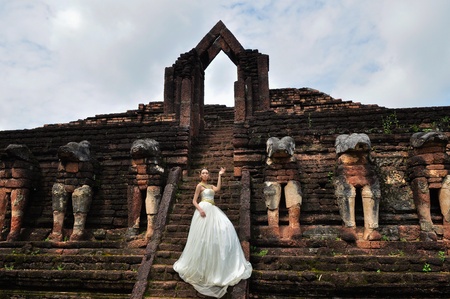 Beautiful woman in Thai traditional dress with Jasmine Thai Garland standing in front of ancient monumentの写真素材