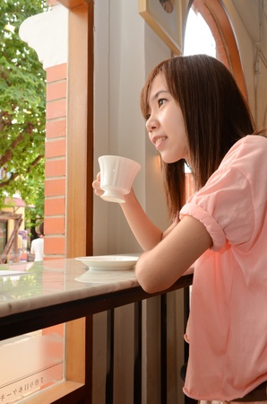 Attractive beautiful woman drinking tea and looking out of the windowのeditorial素材