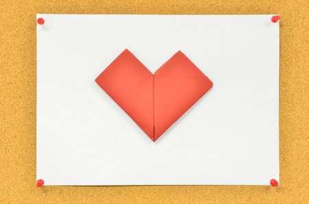 cork board with red heart on white paperの写真素材