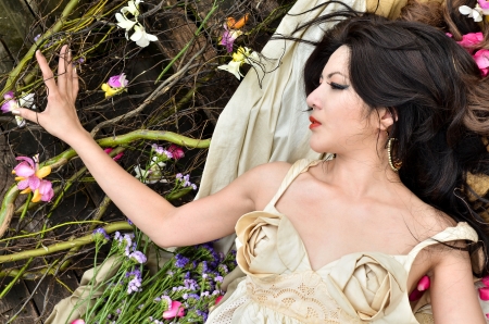 Young beautiful woman sleeping with flowers outdoorの写真素材