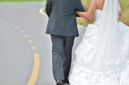 Bride and groom walking away on the roadの写真素材