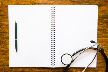 Stethoscope with open blank book and pen on grungy wood backgroundの写真素材