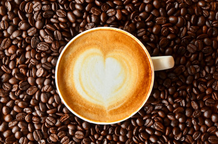 A cup of coffee with heart shape on coffee bean backgroundの写真素材