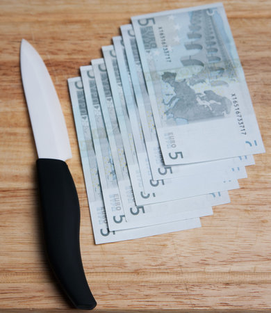 Ceramic knife and money on a wooden chopping board