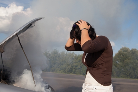 Frustrated woman looking at smoking car engineの写真素材