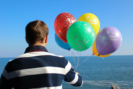 man with balloons on his birthday wathing on seaの写真素材