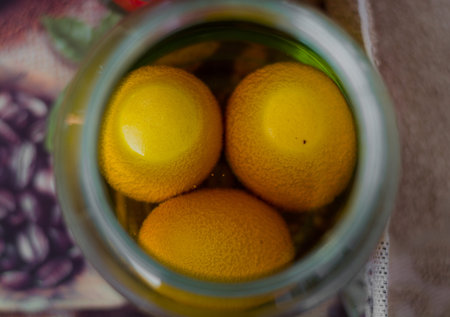 Three eggs in a jar full of yellow paint waiting to become colorful Ð•aster eggs.