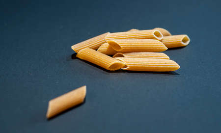 Yellow raw macaroni, a close-up of traditional Italian pasta, uncooked noodles on black background.の写真素材