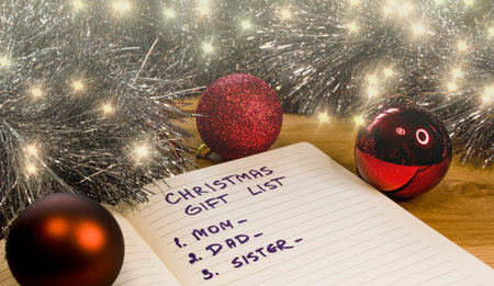An illuminated Christmas gift list. Christmas lights, baubles and other decorations on a wooden...
